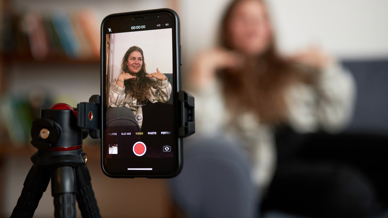A woman talking in front of a smartphone on a tripod.
