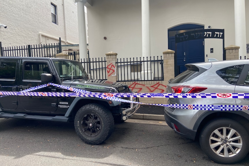 Several red swastikas spray painted across a wall