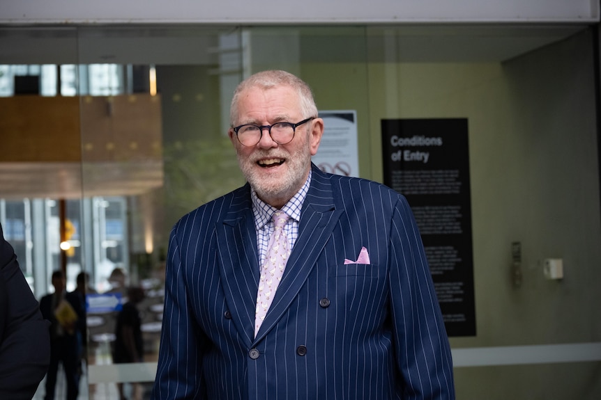 A man in a striped suit and wearing circular glasses.