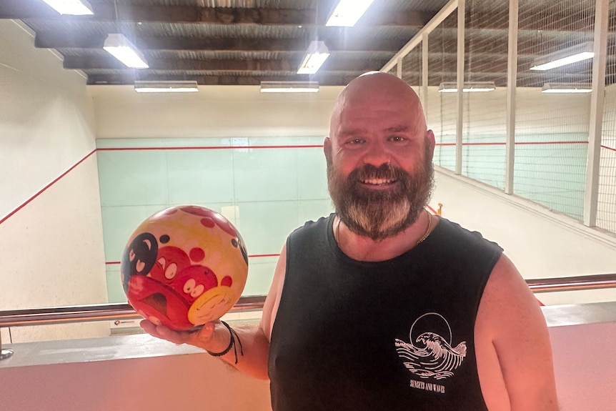 a bald man holding a volleyball