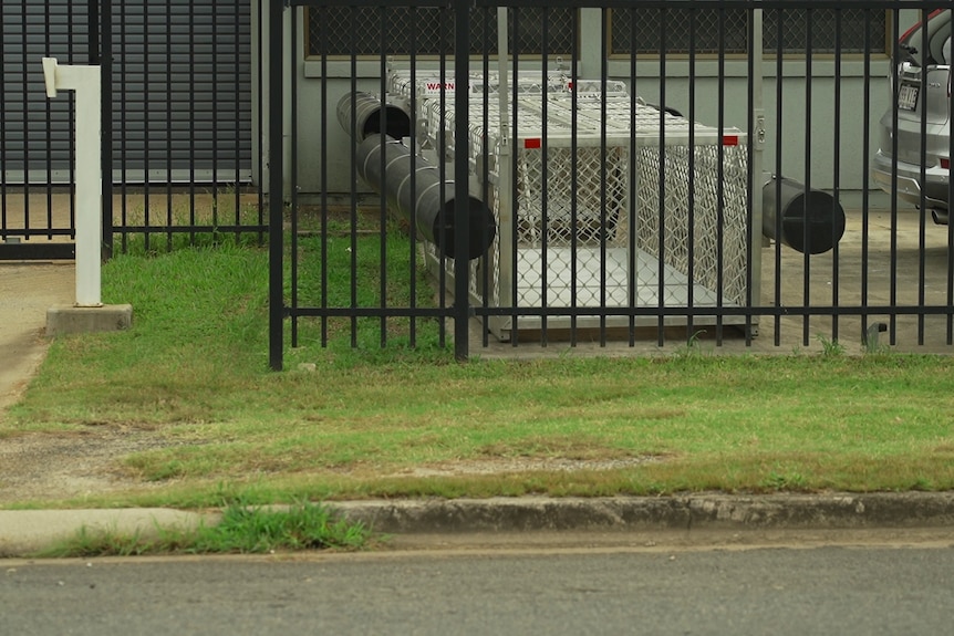 A large rectangular cage behind a fence.