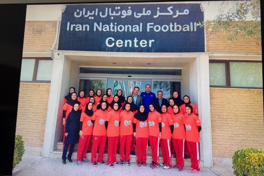 A football team pose together outside "Iran National Football Center"