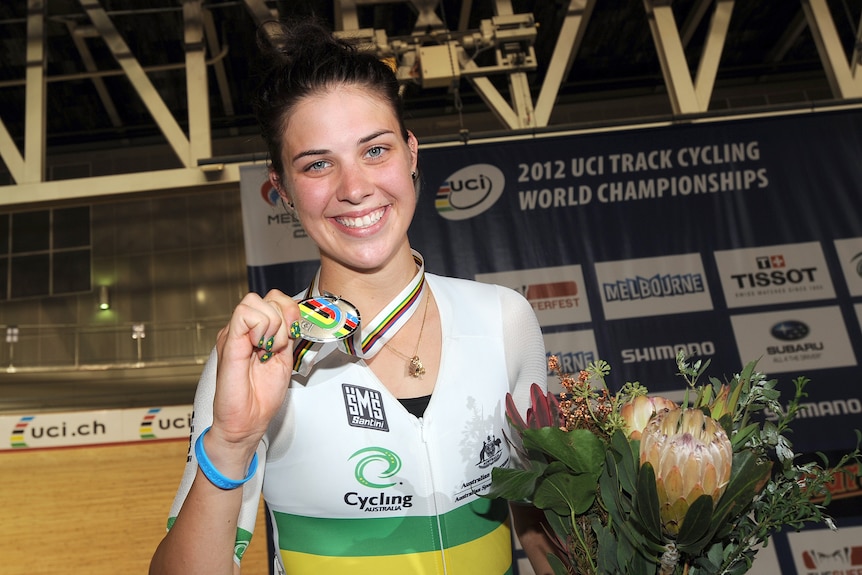 A woman smiles with a medal.