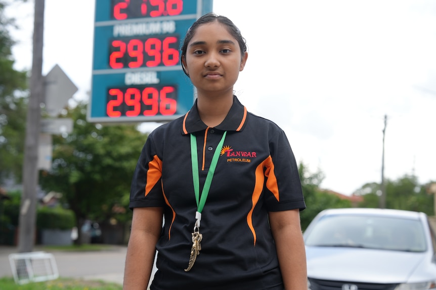 Gunveet stands in front of an LED petrol price sign.