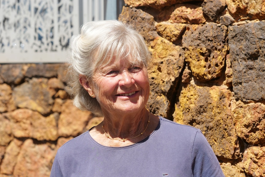 older woman with short grey hair and blue top smiling