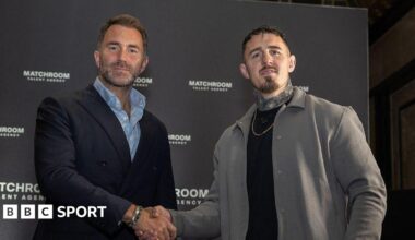 Eddie Hearn and Tom Aspinall shake hands and look at the camera