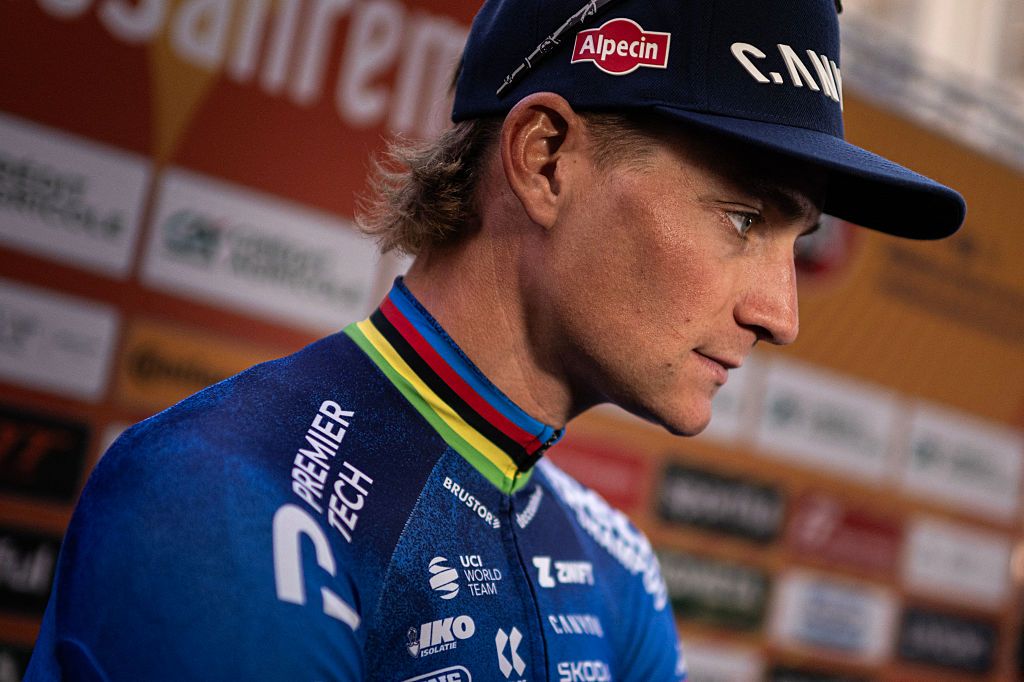 A close profile view of Mathieu van der Poel in his cycling kit with rainbow trimmed neck and a ballcap