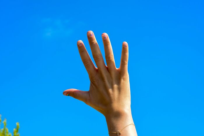 Hand raised against blue sky representing patients faking it in medical cases according to medical pros online.