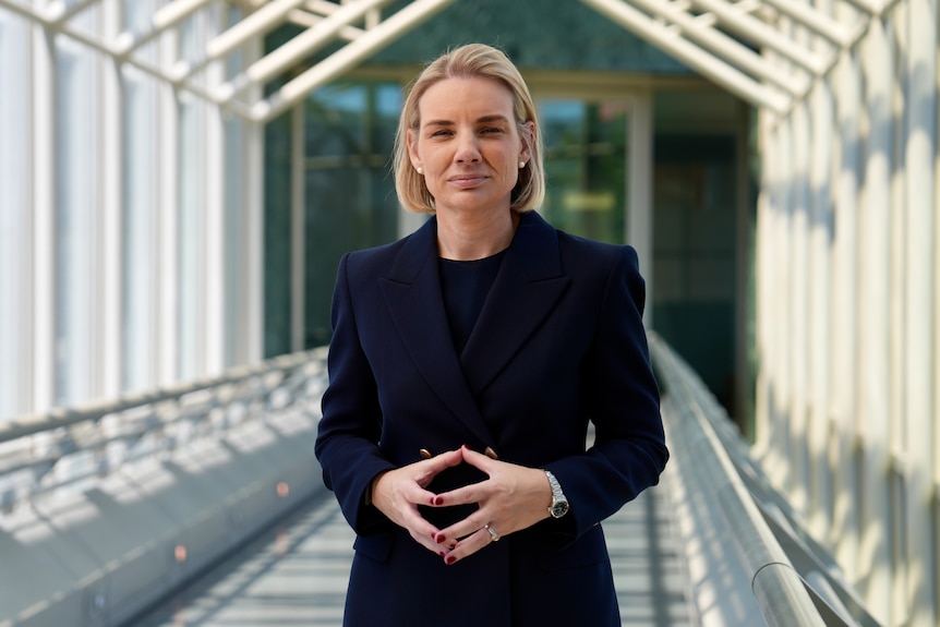 Woman in a navy suit standing on a bridge.