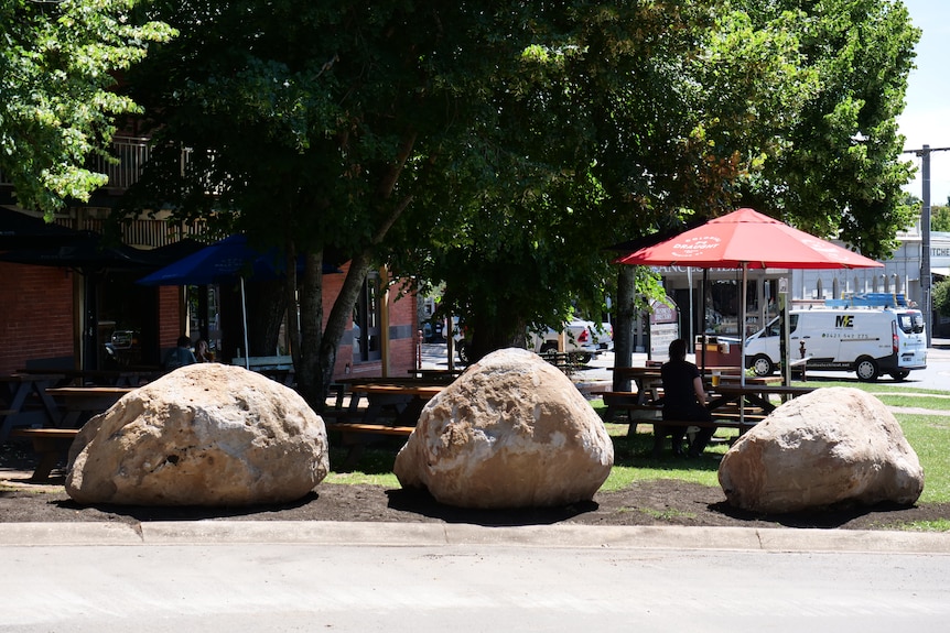 Three large rocks sit on the edge of the road