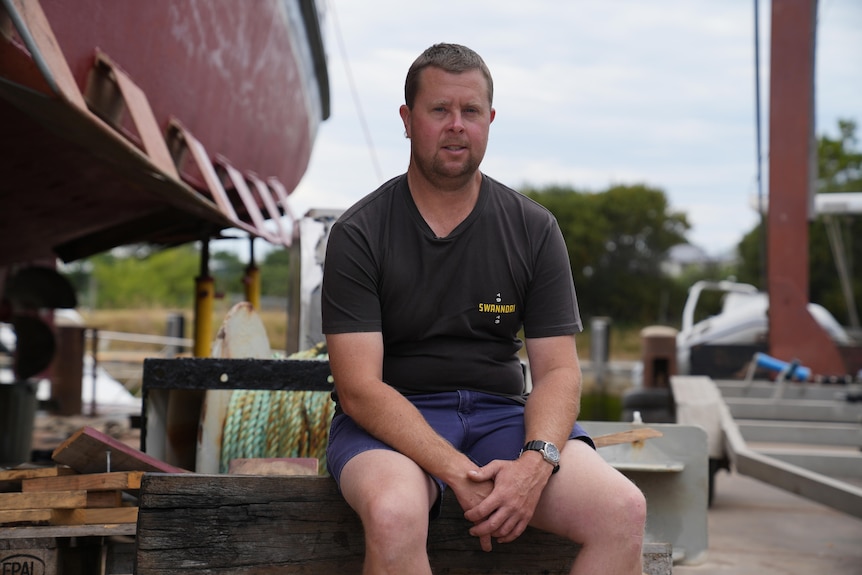 He sits on a bench in a ship yard