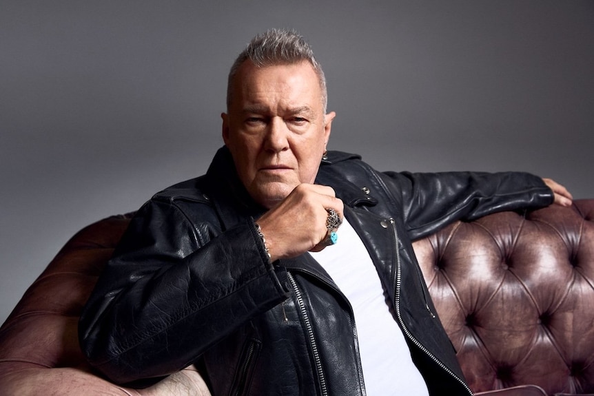 Jimmy Barnes sits on a couch looking serious