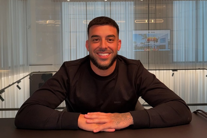 Adrian Portelli sitting with his hands folded on a table