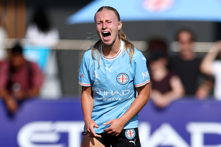 A woman with long hair, wearing a light blue jersey, on the field.
