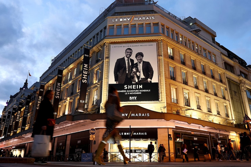 A building lit up at night with Shein banners alongside the side 