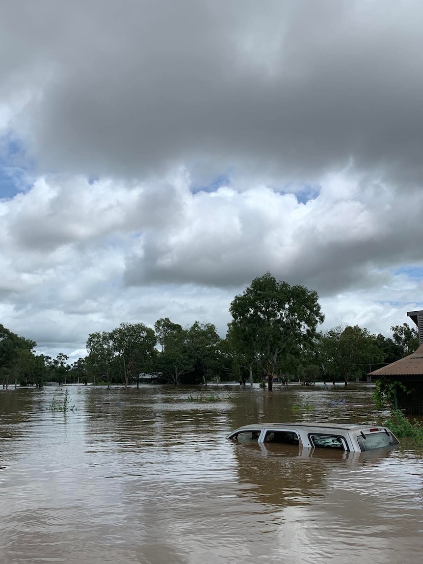 Floodwaters almost up to the roof of a car, in a remote community.