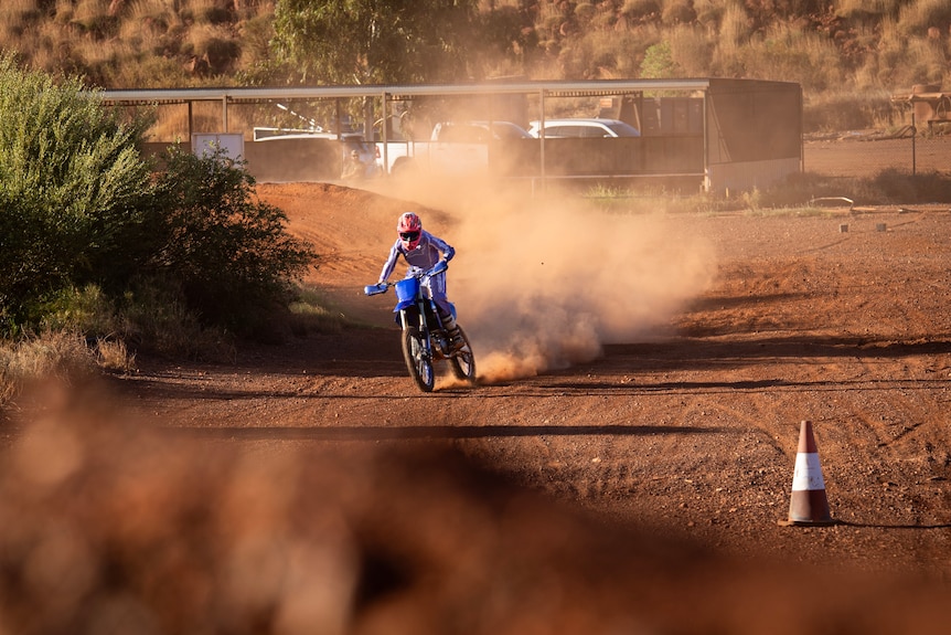 A motor bike rider kicks up dust