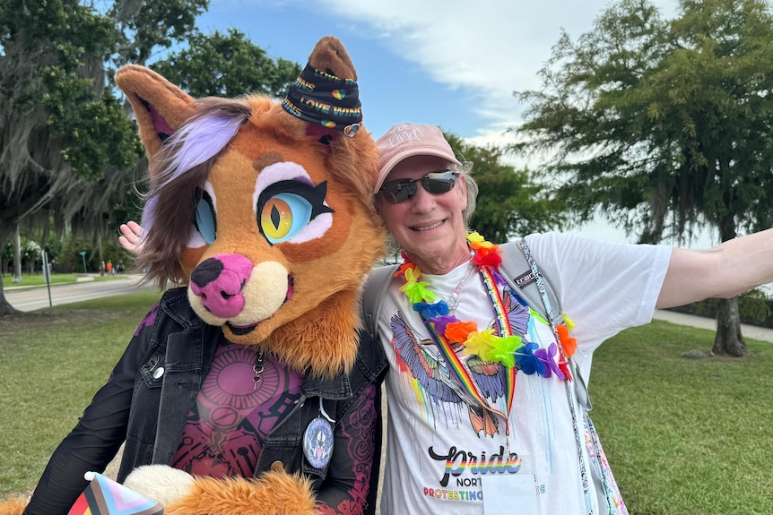 Lisa Sicard smiles in park with rainbow decorations on and next to someone dressed up as a cat
