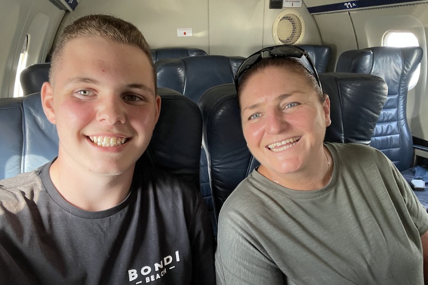 A boy with a short hair cut smiles next to a woman with sunglasses on her head.