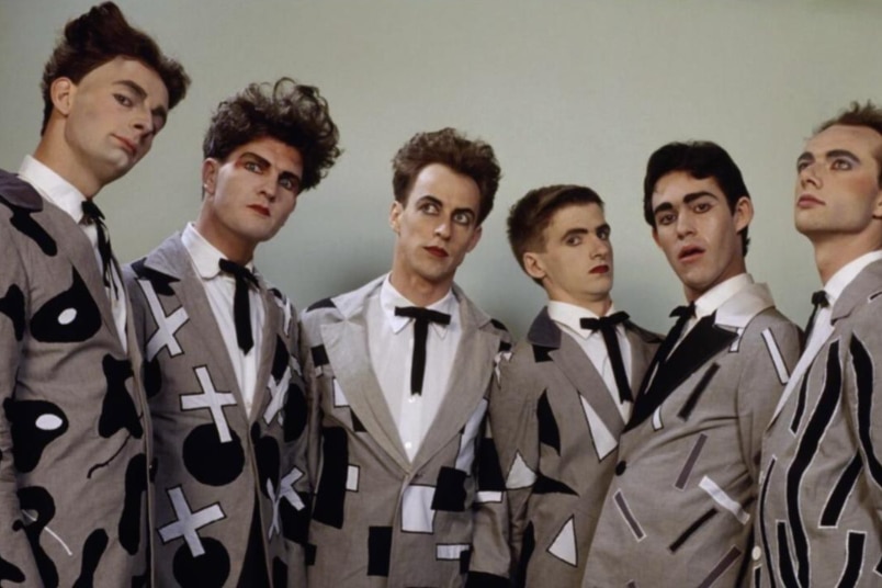 vintage pic of six men from band split enz wearing grey, patterned suits 