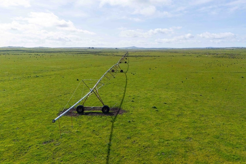 A long spraying machine runs across a field on the property.