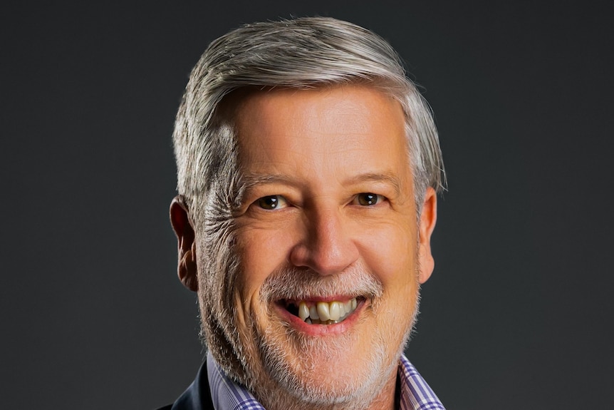 A headshot of a man with white hair