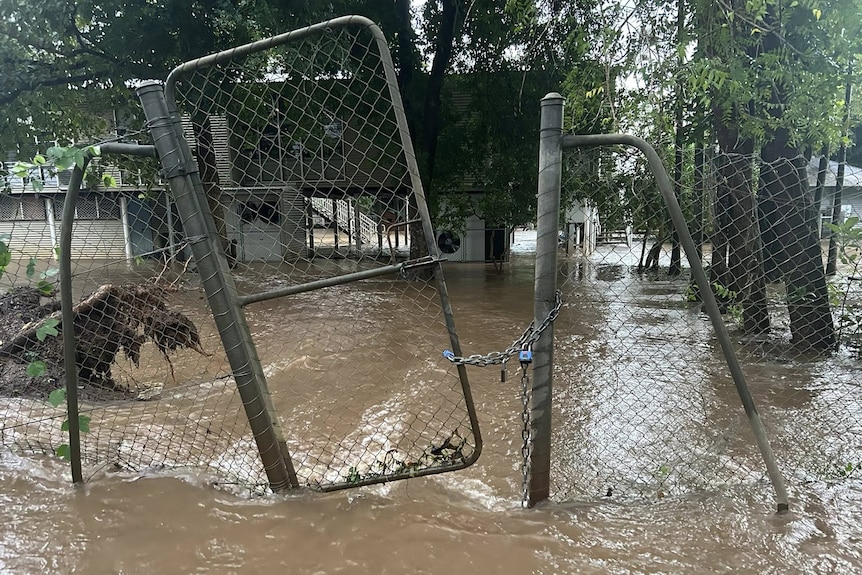 A gate and fence surrounded by floodwaters