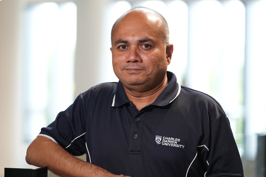 A man in a polo shirt looks at the camera