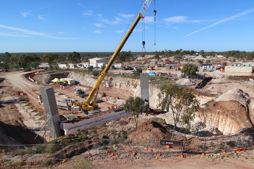 A construction site where hills of dirt surround a huge crane laying 12-metre high walls made of concrete 
