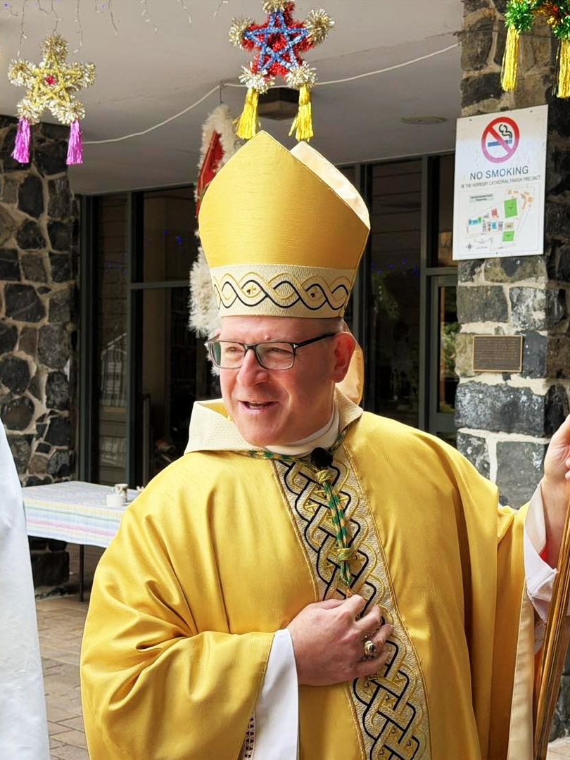a man in yellow church robes and hat, holding a golden cane