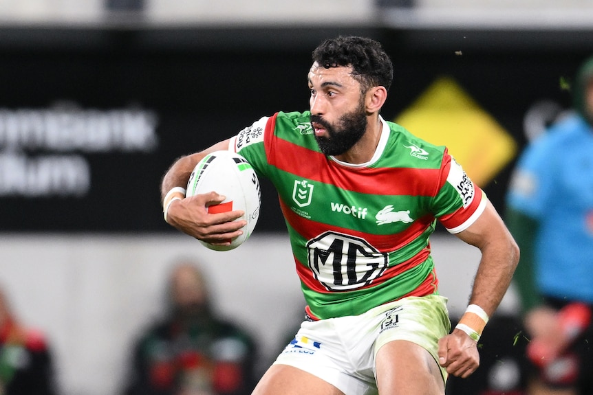 A man runs the ball during a rugby league match