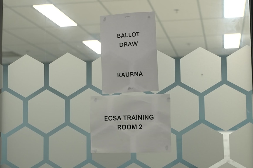 A sign printed on paper, stuck to a wall, indicating a ballot room. 