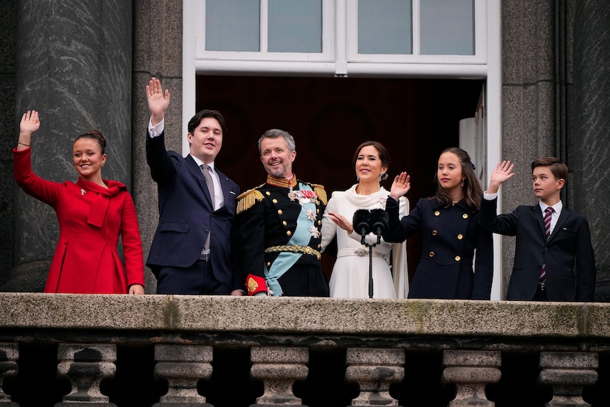 A group of people waving on a balcony
