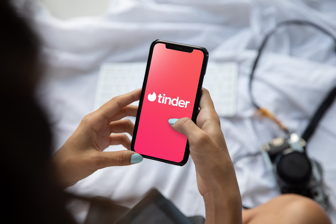 Tinder's logo on a phone screen held by a woman