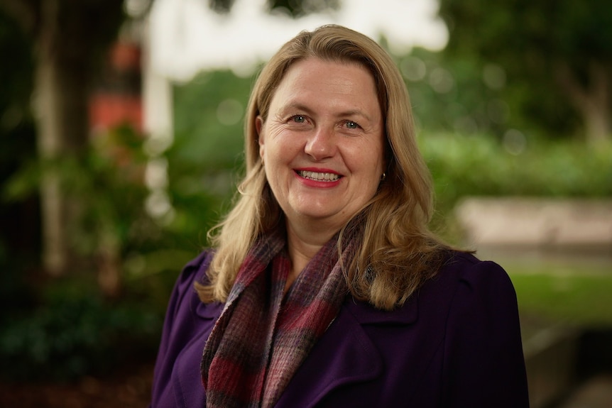 a woman with dark blonde hair smiles