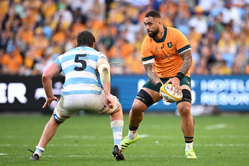 Lukhan Salakaia-Loto of Australia looks to pass the ball with a defender about to tackle him