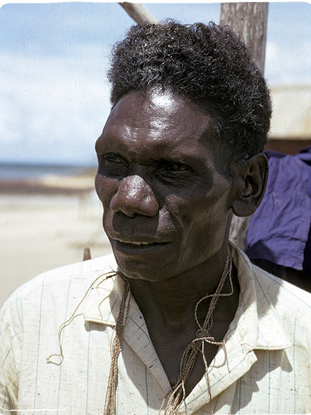 An Aboriginal man stands outside wearing a white collared shirt.
