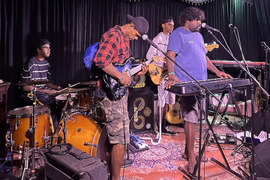 Four DMC band members performing on a stage and playing a range of instruments