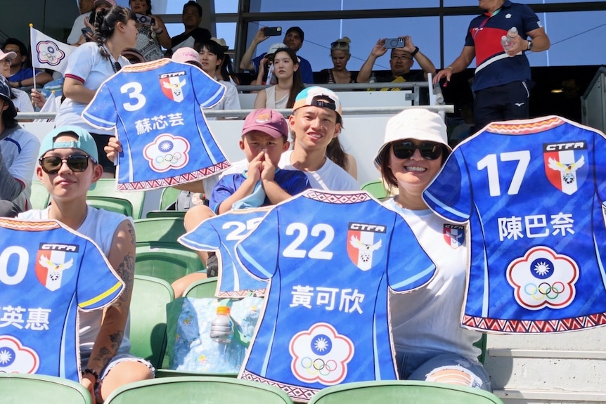 A crowd in a soccer game holding up jerseys and smiling