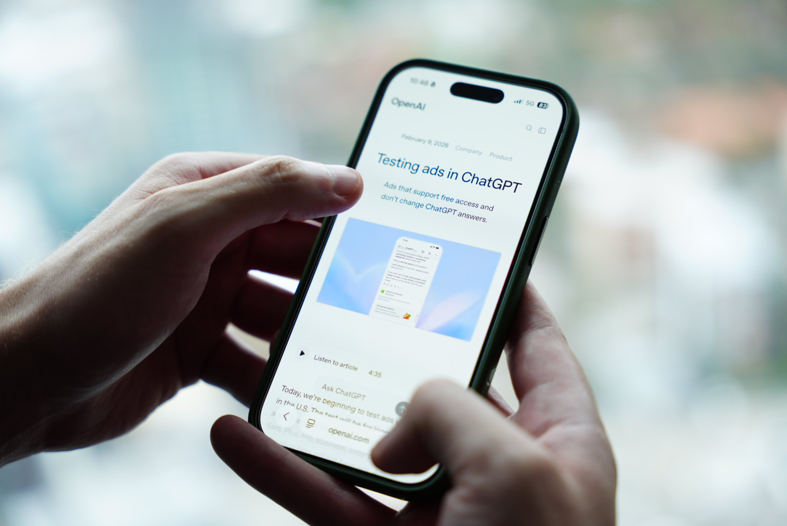 a person holding a mobile phone that shows the words testing ads in chatgpt on the screen