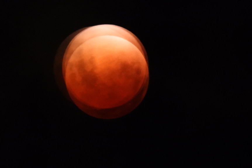 An overlay of one moon over another, both in bright orange.