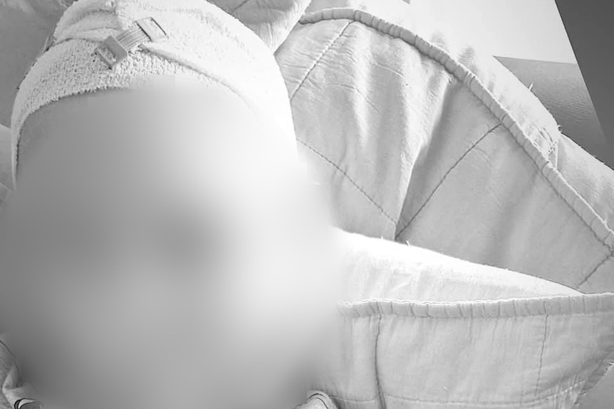 A blurred black-and-white photo of a small boy with a bandaged head.