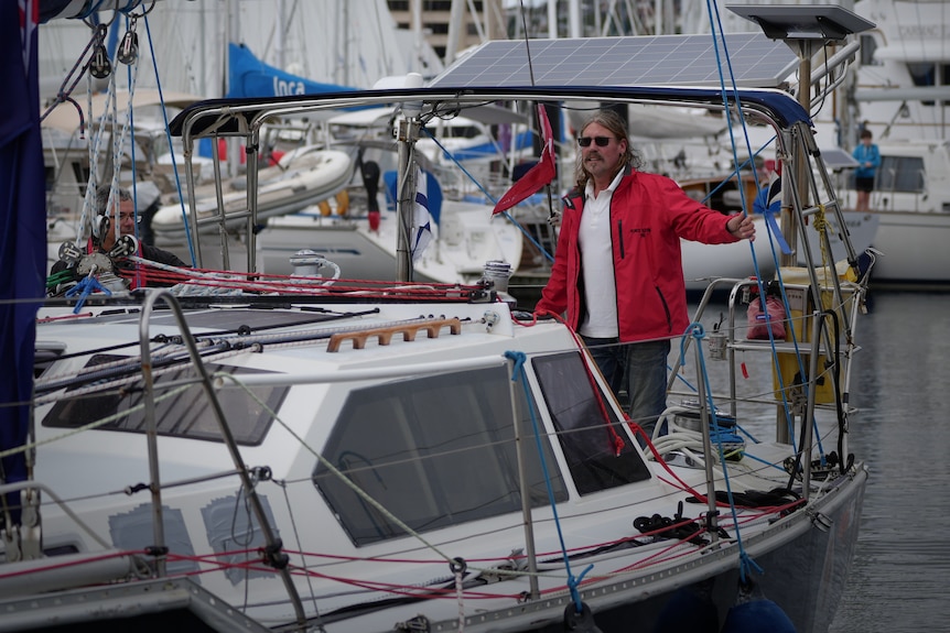 A man in a red windbreaker on a yacht.