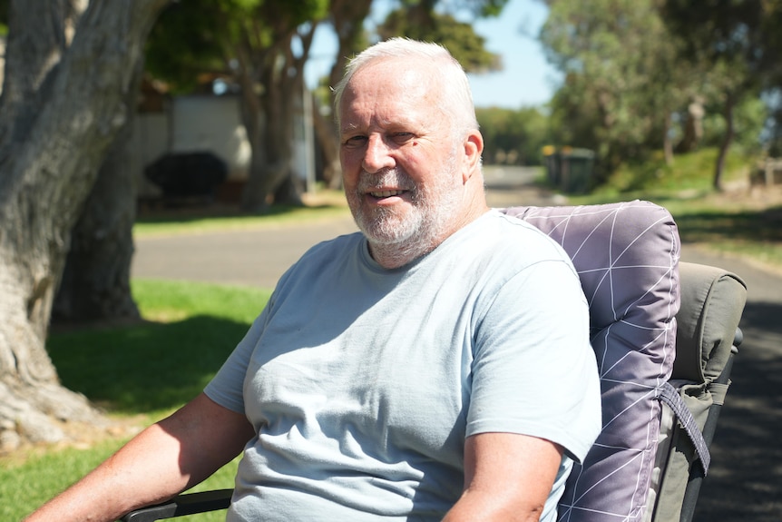 Rob Barker sits in a chair at a caravan park.