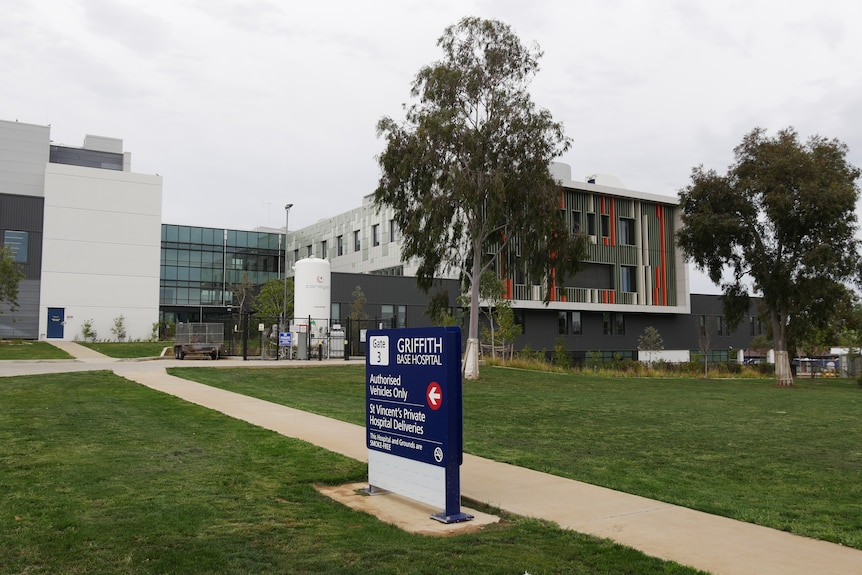 A lawn in front of a multi-storey hospital.