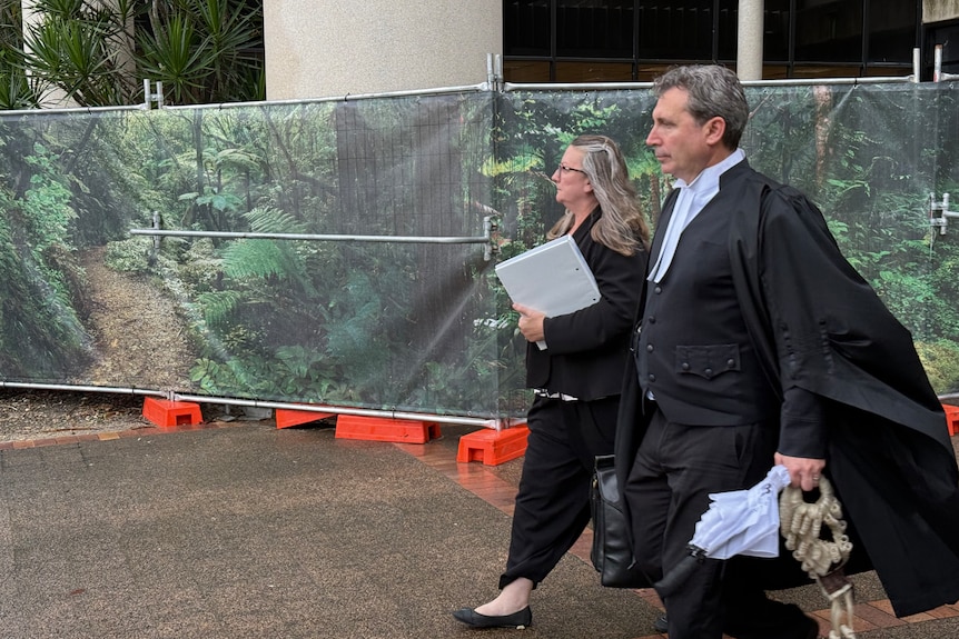 A barrister in robes walking on a pavement