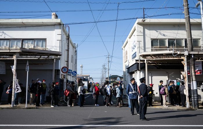 Fans line up near closed shops as they wait for a bus to the race track.