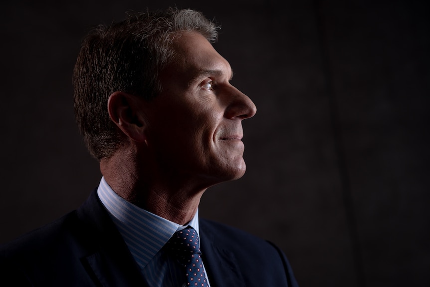 A side profile of a man's face wearing a suite and tie