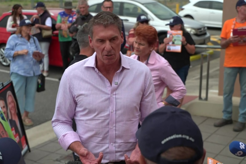 A man and a woman speak to people while media is around