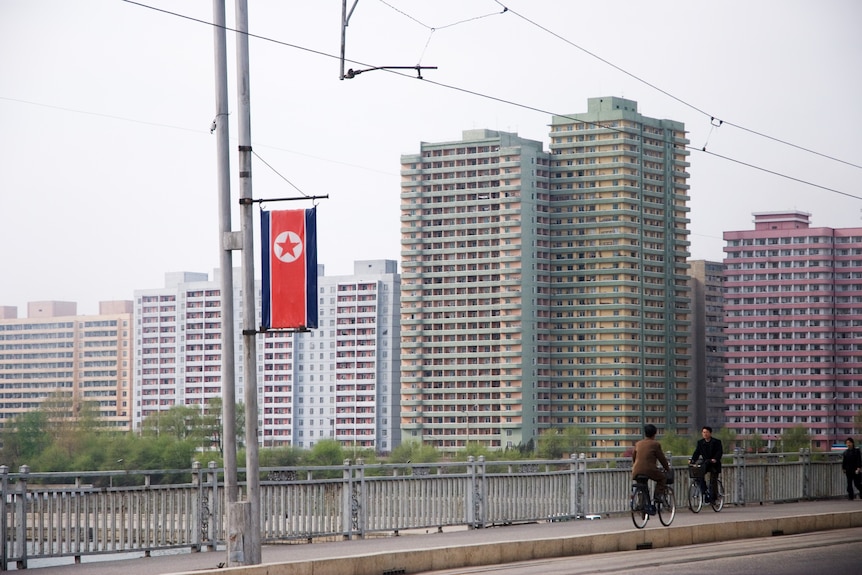 People cycle over a bridge in Pyongyang